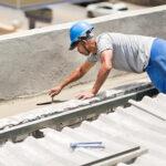 Shot of a mason worker wearing hardhat constructing a rooftop with concrete