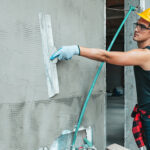 Industrial worker on construction site laying sealant for waterproofing cemen